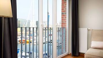 A room with a view of a marina, a sofa, a lamp, and a radiator.
