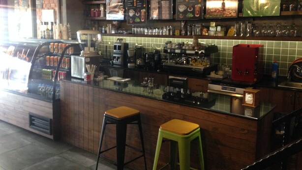 A bar area with a menu board, stools, and bar equipment. - Yalcin Hotel (Antalya)