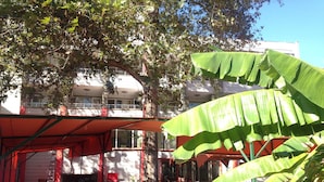An outdoor seating area with tables and chairs, surrounded by trees and a building in the background. - Yalcin Hotel (Antalya)