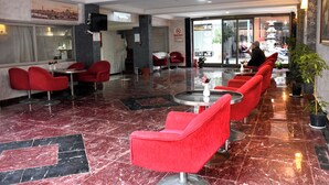A hotel lobby with red chairs, a reception desk, and a staircase leading to the upper floor. - Yalcin Hotel (Antalya)