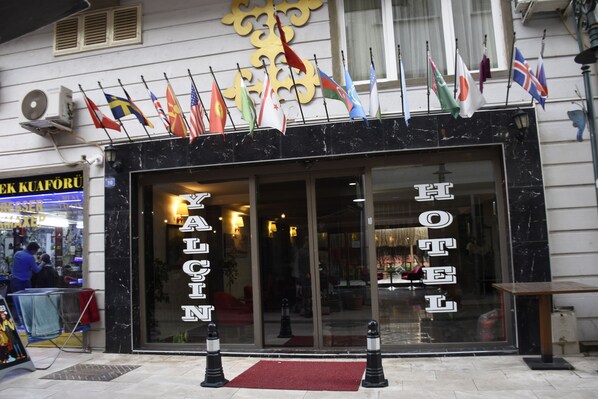 Fachada de un hotel con varias banderas en el exterior.