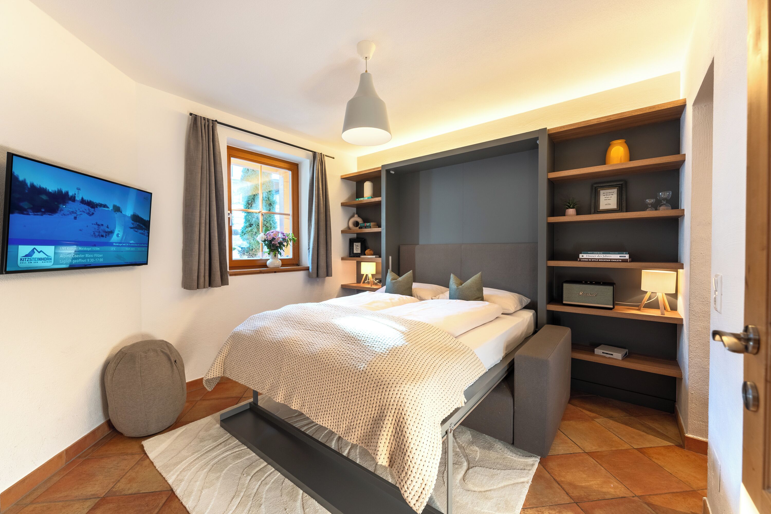 Un dormitorio moderno con cama, mesitas de noche, televisor y estantería empotrada.