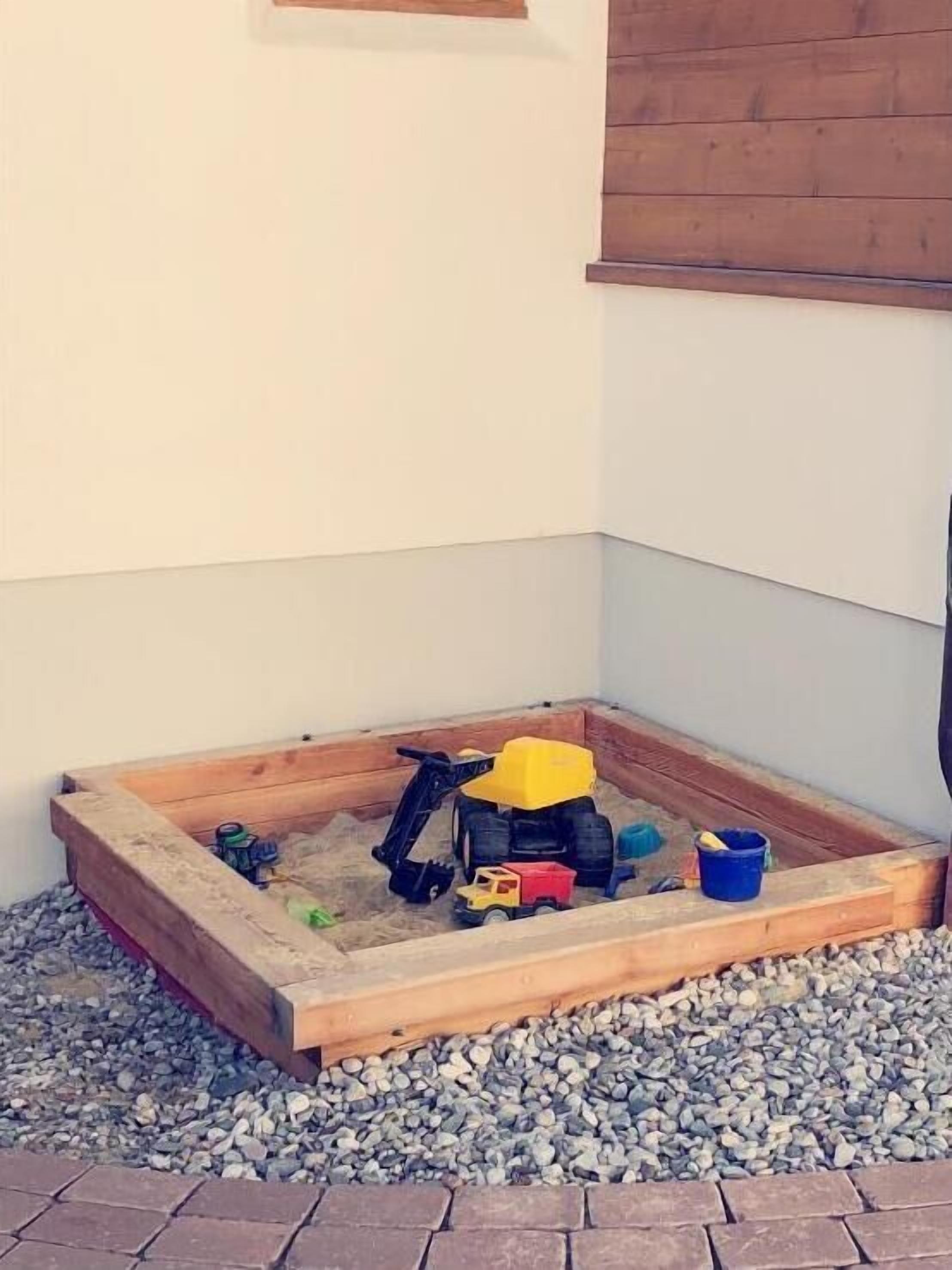 Een zandbak met speelgoed en een houten rand.