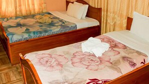 A room with two wooden beds, each with floral bedding. - Hotel Delight Inn (Pokhara)