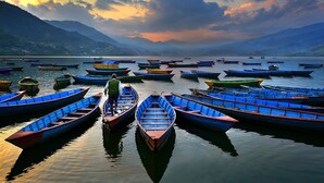 A calm lake with numerous small boats docked at the shore. - Hotel Delight Inn (Pokhara)