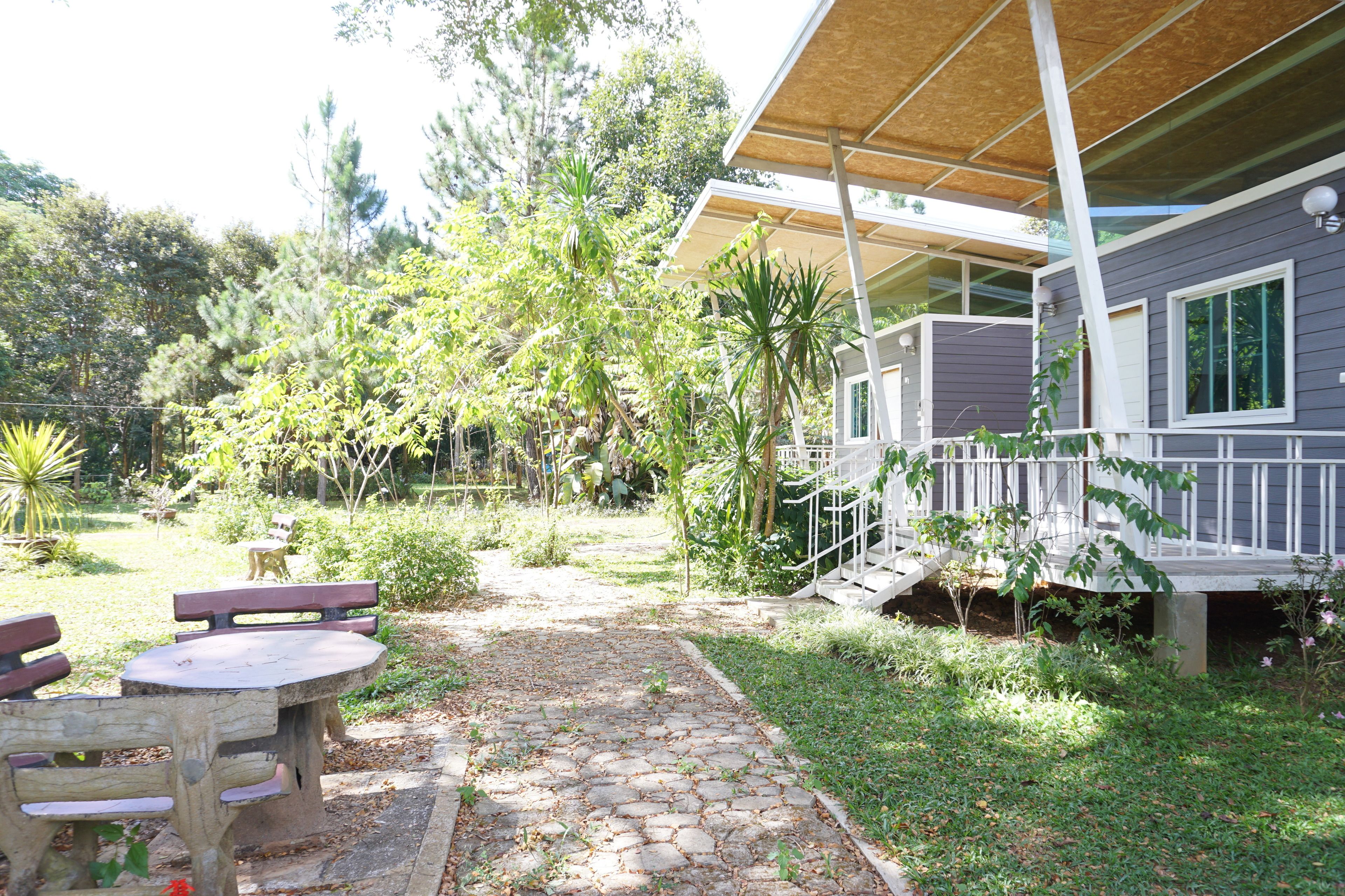 A covered outdoor area with a stone pathway leading to a wooden table and benches.