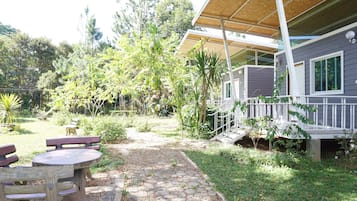 A covered outdoor area with a stone pathway leading to a wooden table and benches.