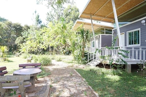 A covered outdoor area with a stone pathway leading to a wooden table and benches.
