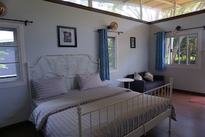 Een slaapkamer met een bed, een tafeltje, een bank en gordijnen.