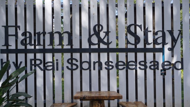A wooden bench with a rustic table in front of a fence with the text "Farm & Stay by Rai Sonseesaed". - Sonseesaed Farm (Phu Ruea)
