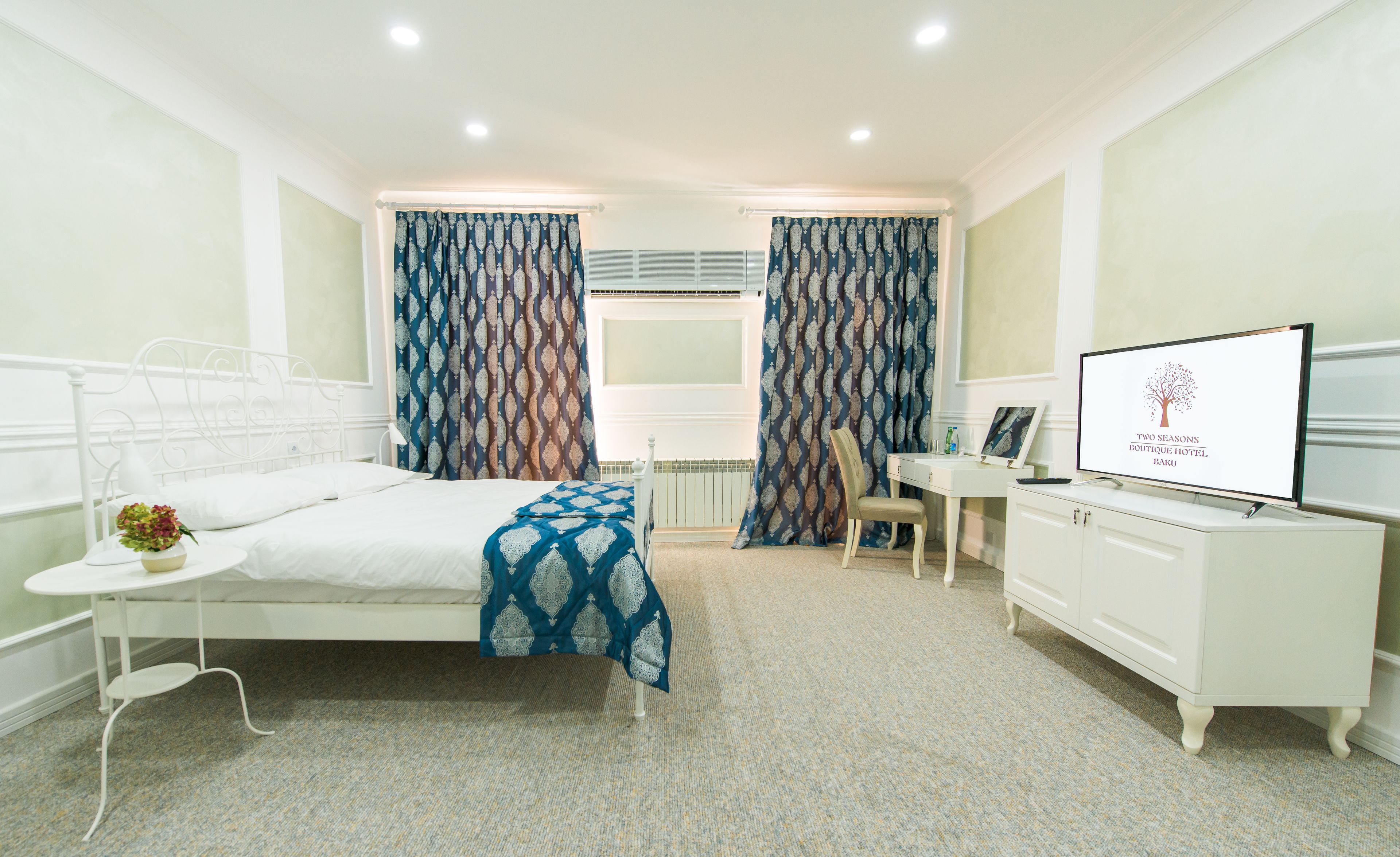 A hotel room with a bed, a desk, a chair, a TV, and curtains.