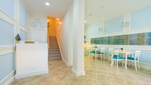Zona de recepción de un hotel con una escalera que lleva a un comedor.