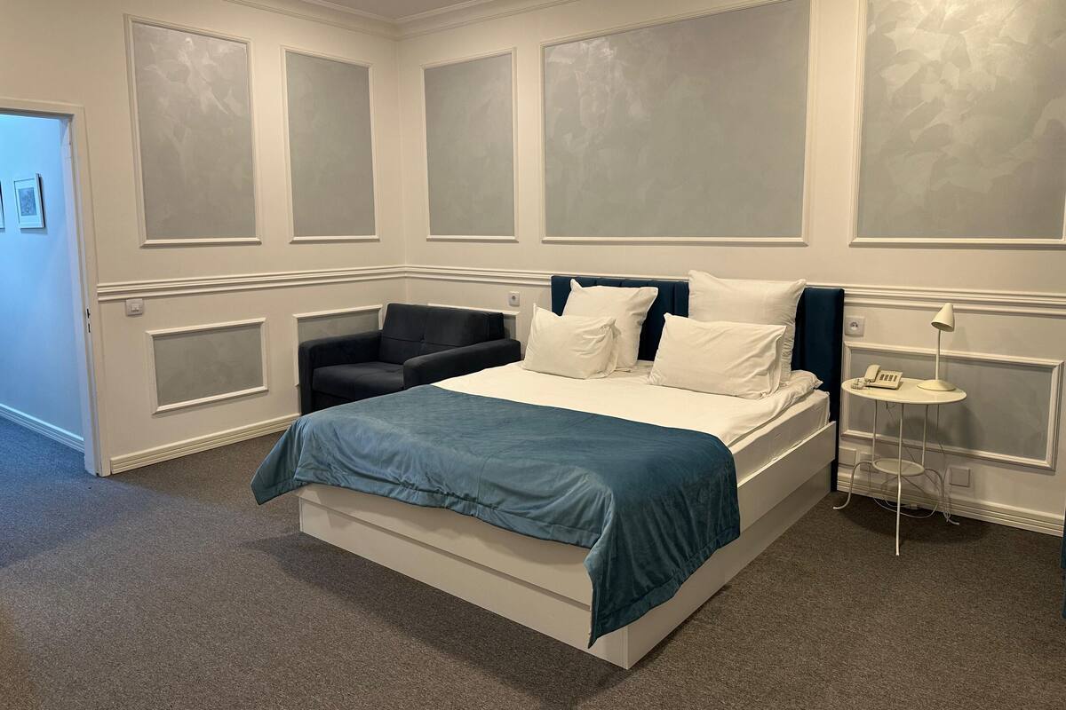 Una camera da letto con un letto, un comodino con una lampada e una sedia.