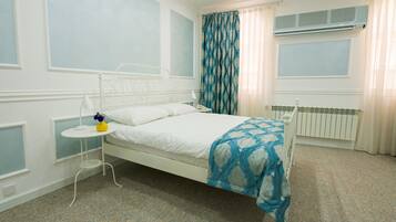 Ein ordentlich eingerichtetes Schlafzimmer mit einem Einzelbett, einem Nachttisch mit Lampe und einem Fenster mit Vorhängen.