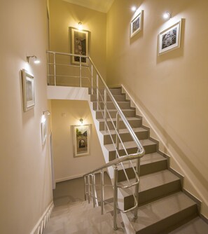 A staircase with a metal handrail, beige walls, and framed pictures.