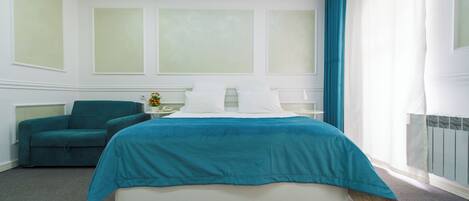 A bedroom with a bed, a chair, a nightstand, and a window with curtains.