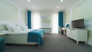 Habitación de hotel con cama, escritorio, televisor y radiador.