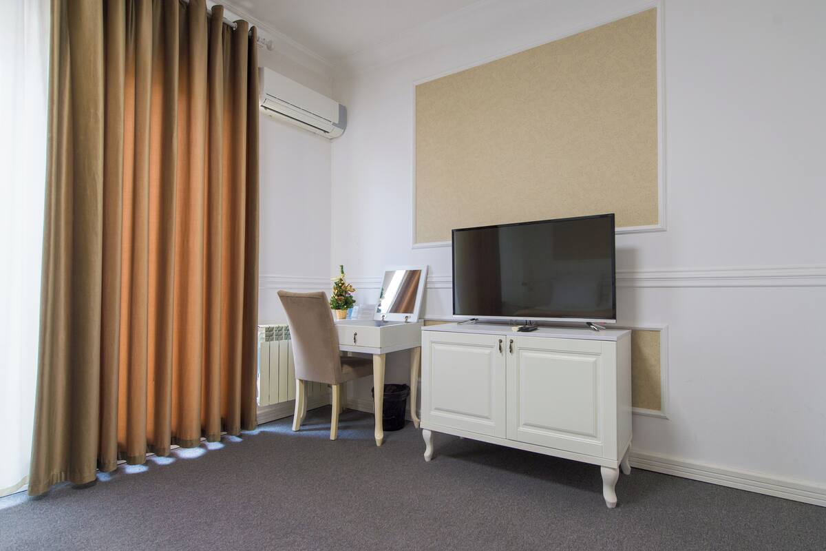 Una camera d'albergo con una scrivania, una sedia, televisore e un armadio.
