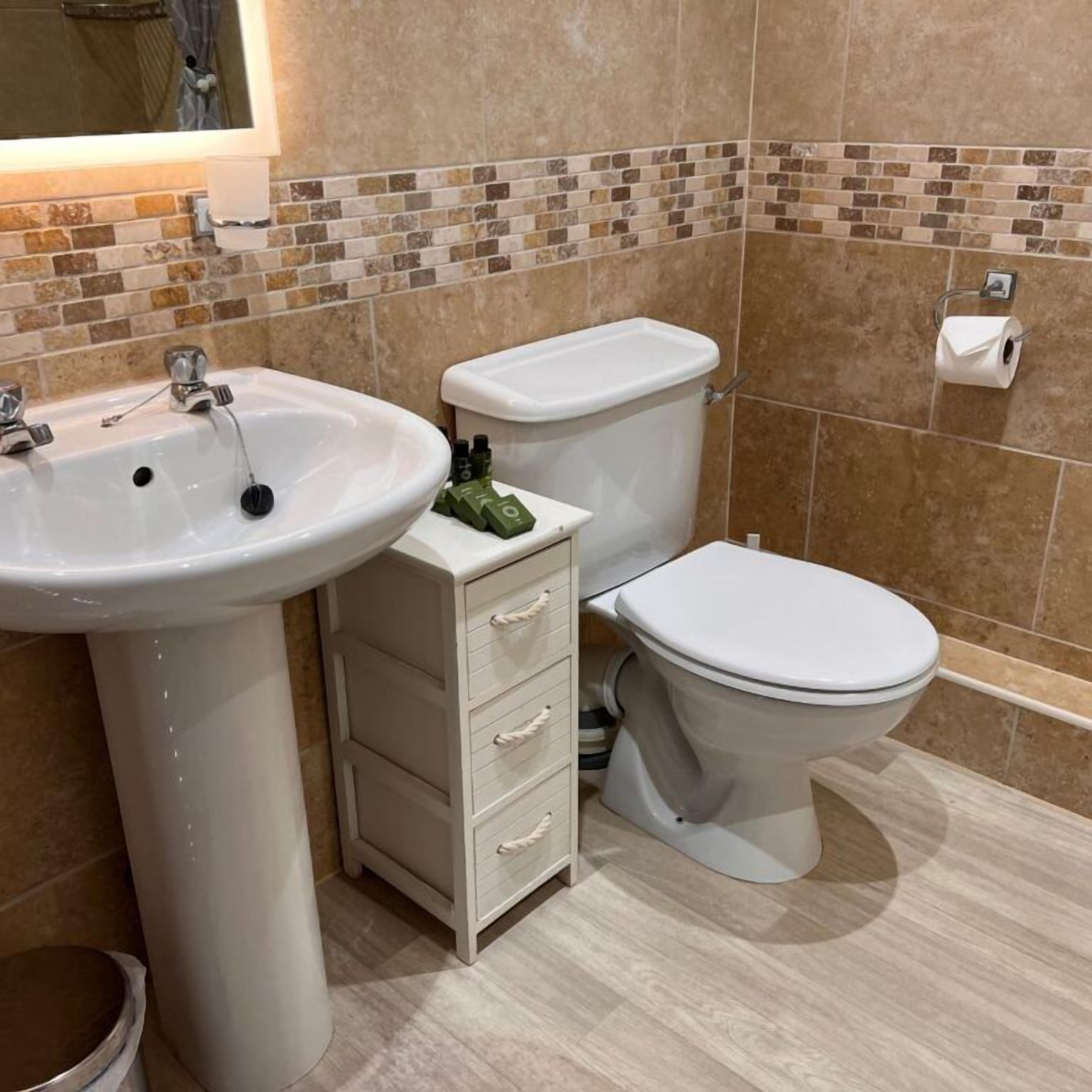 A bathroom with a sink, toilet, and a small cabinet.