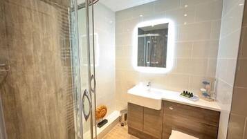 Un baño moderno con cabina de ducha de vidrio, tocador con espejo y inodoro.