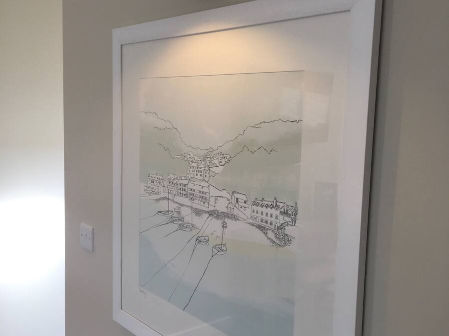 A framed black and white cityscape artwork on a wall, a black wall-mounted lamp, and a white switch.