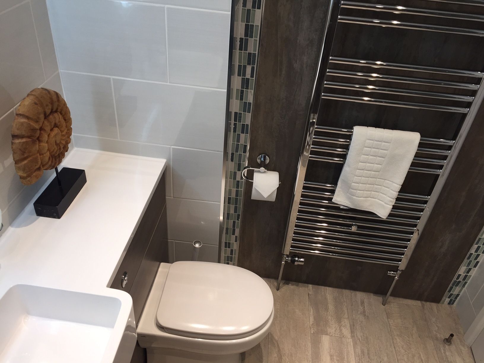 A modern bathroom with a toilet, a sink, a towel rack, and a decorative item on the counter.