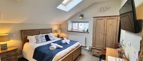 A bedroom with a bed, bedside table, wardrobe, and a skylight.