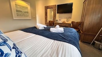 A hotel room with a bed, a television, a wardrobe, and a painting on the wall.