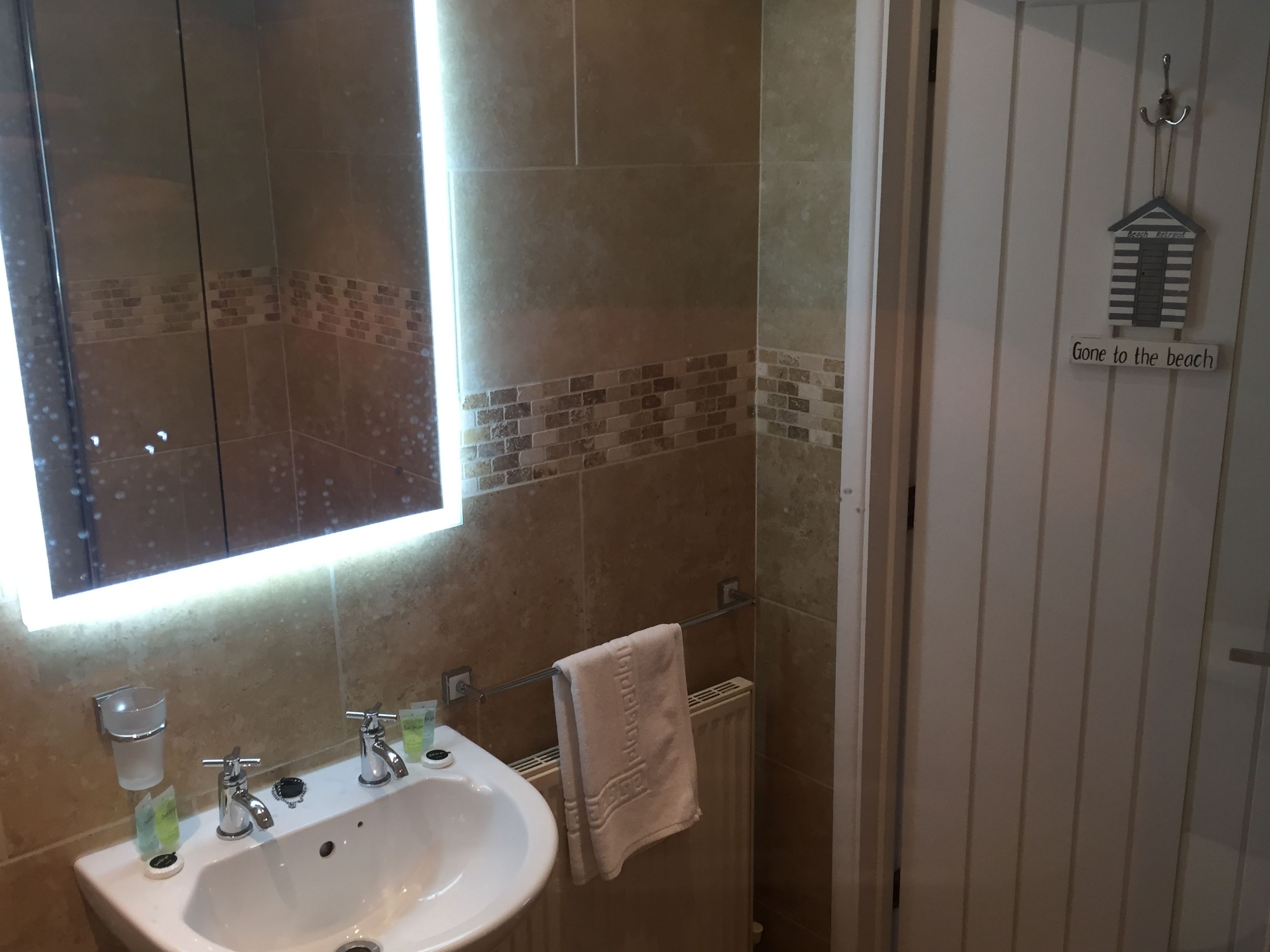 A bathroom with a sink, mirror, and towel rack.