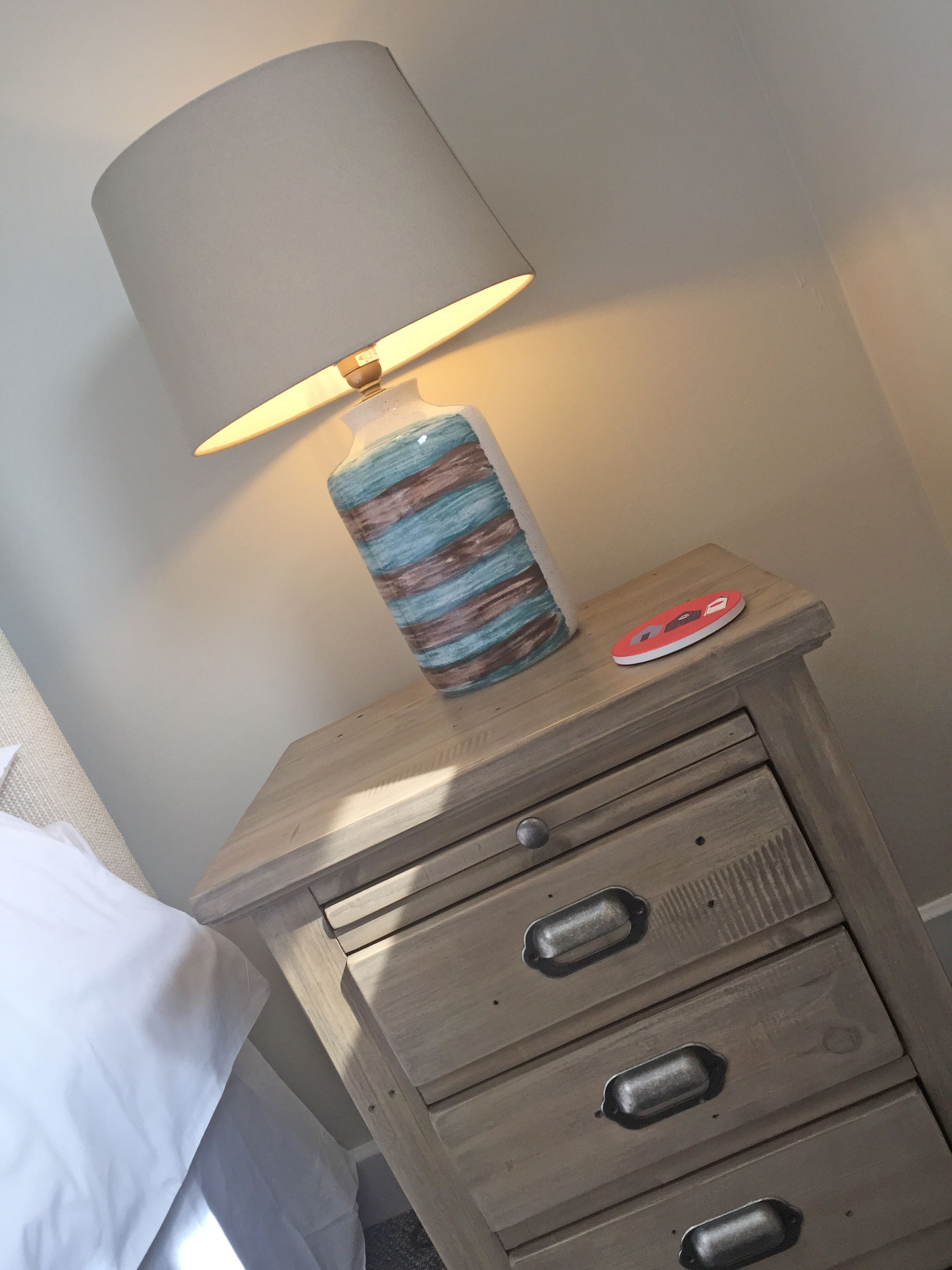 Ein Nachttisch aus Holz mit einer Lampe und einem Teller.