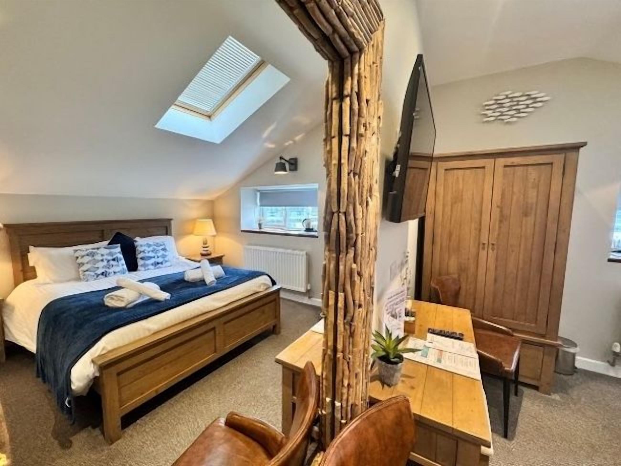 A bedroom with a bed, a desk, a chair, a window, and a wardrobe.