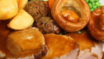 A plate of food including roast beef, Yorkshire pudding, Yorkshire pudding with egg, and vegetables.