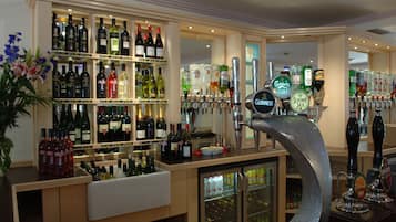 Zona de bar con estantes de bebidas embotelladas, sistema de grifos y un refrigerador.