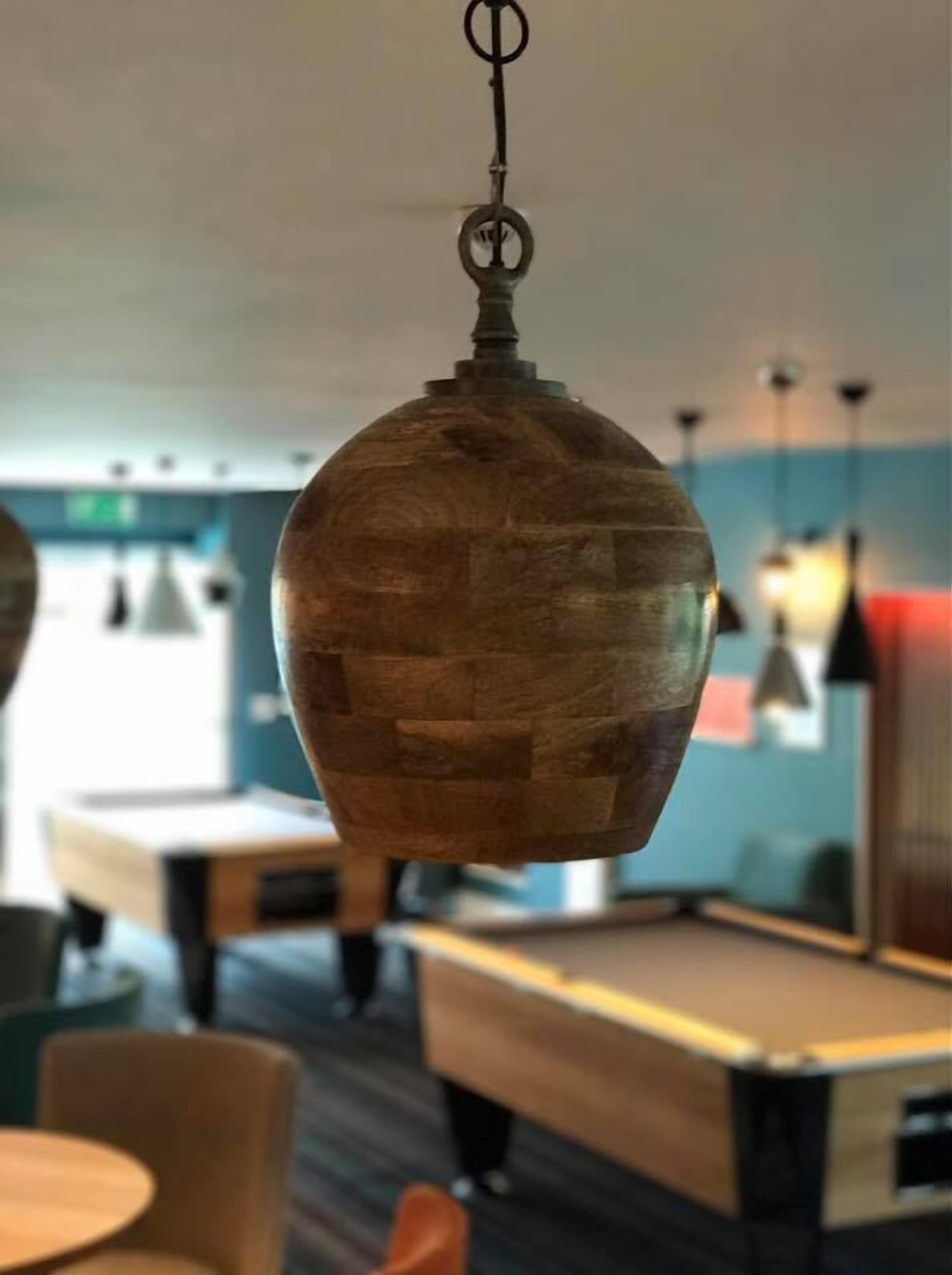 A hanging wooden pendant light fixture in a modern interior space.