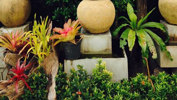 A sign for Suchada Palace with a decorative stone stack and lush greenery. - Suchada Palace (Thung Song)