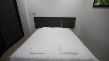 Una cama bien hecha con sábanas blancas y dos toallas dobladas sobre la cama.