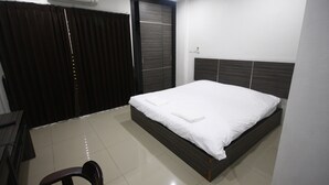 A modern bedroom with a large bed, a desk, and a chair. - Suchada Palace (Thung Song)
