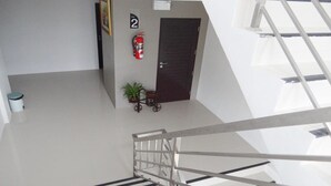 A modern interior with a staircase, a fire extinguisher, a door marked '2', and a small plant. - Suchada Palace (Thung Song)