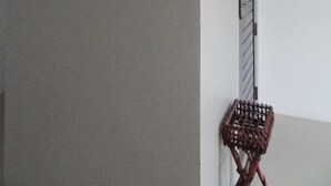 A room with a framed landscape painting, a red fire extinguisher, and a wicker basket. - Suchada Palace (Thung Song)