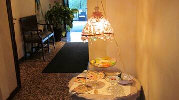 Un couloir avec une table où sont exposés divers produits alimentaires, une lampe suspendue et une chaise.