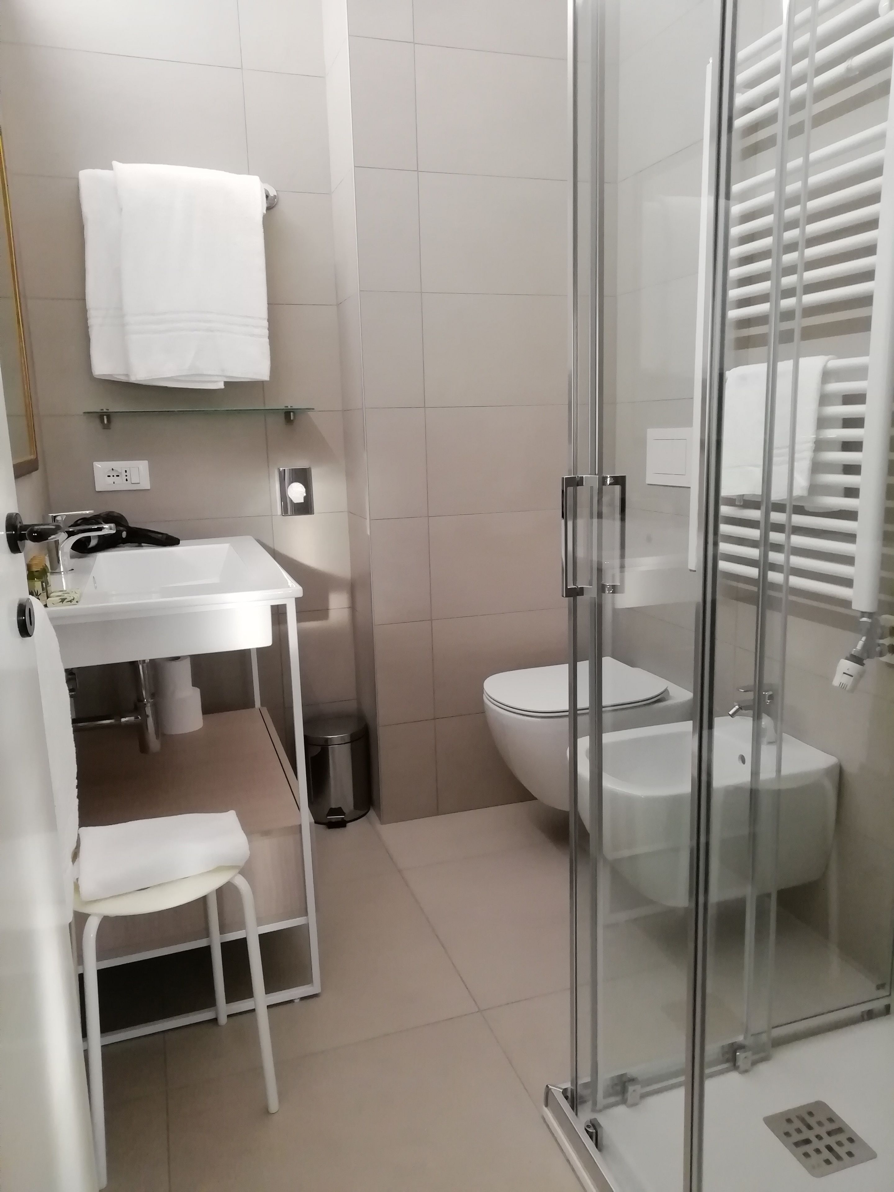 A modern bathroom with a glass shower enclosure, a white sink, and a toilet.
