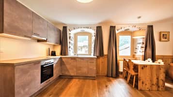 Una cocina moderna con armarios de madera, horno empotrado y comedor con mesa y sillas de madera.