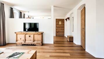 A modern living room with a wooden cabinet, a flat-screen TV, and a wooden floor.