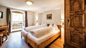 Una cama doble con sábanas blancas, un escritorio de madera y un armario de madera grande.