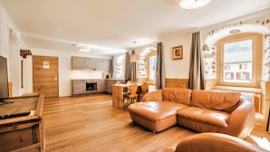 Una sala de estar moderna con un sofá de cuero, piso de madera, un comedor y una cocina.