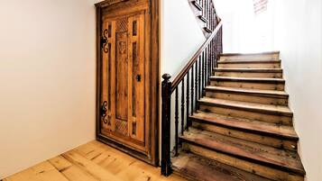Un escalier en bois avec une rampe et une grande porte en bois ornée d’éléments décoratifs.