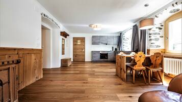 A spacious kitchen with wooden cabinets, a dining area with wooden chairs, and a stone accent wall.