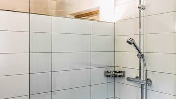Una doccia moderna con soffione a mano e rubinetto a parete, con pareti rivestite di piastrelle bianche e un soffitto decorato.