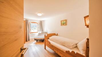 Un letto di legno in una stanza con una finestra, una sedia e un quadro appeso al muro.