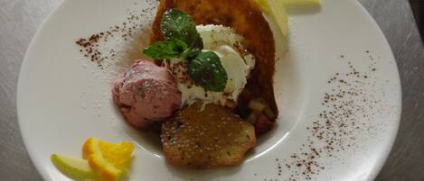 A dessert plate with ice cream, a fruit slice, and a pastry.